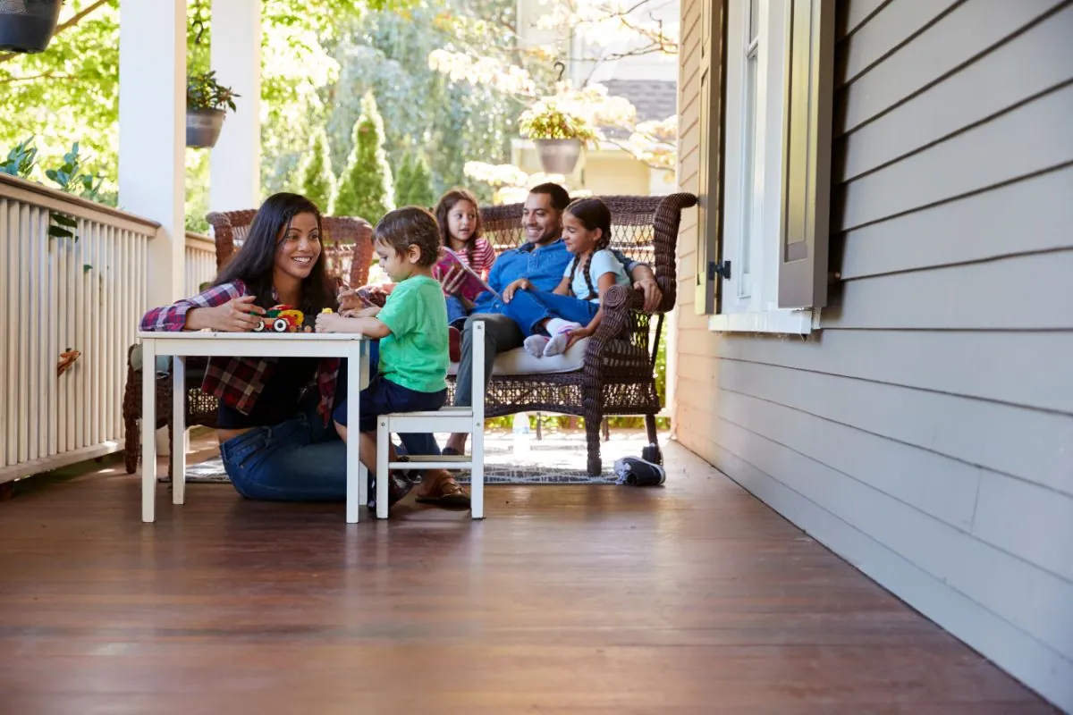 family sit on back porch of the house